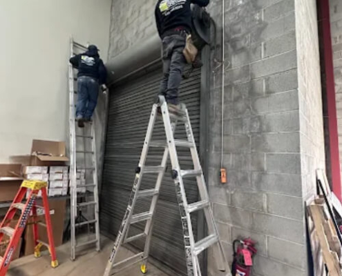 NYC commercial garage door installation technicians wire garage door motors for a metal rollup door.