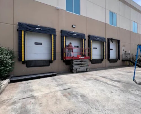 New York garage door repair service technician fixes damaged commercial doors at a warehouse.