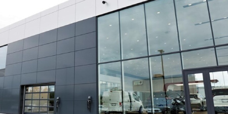 NY auto dealership glass panel garage door installation by Garage Door Customs.